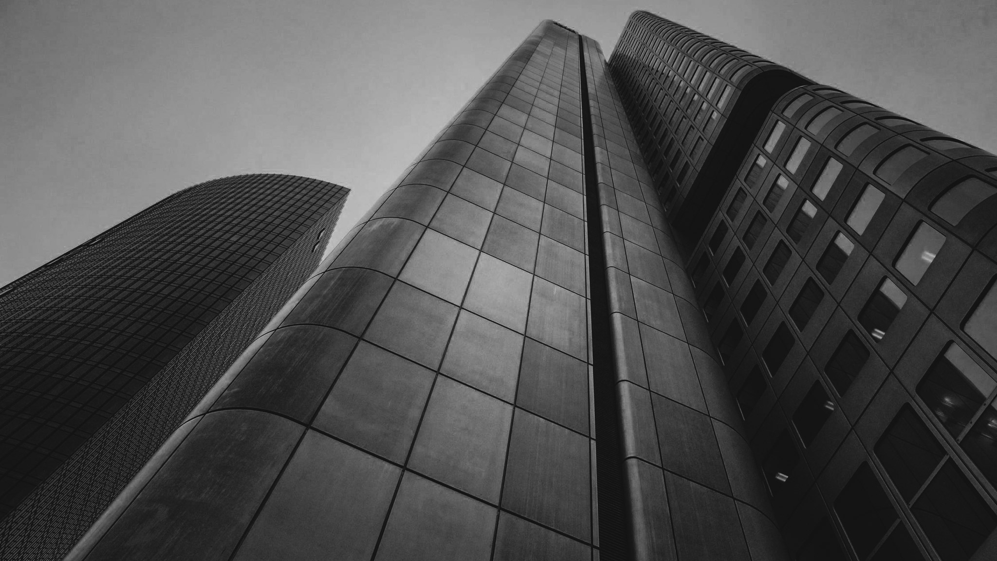Low-angle view of three modern high-rise office buildings with glass and metal facades against a clear sky.